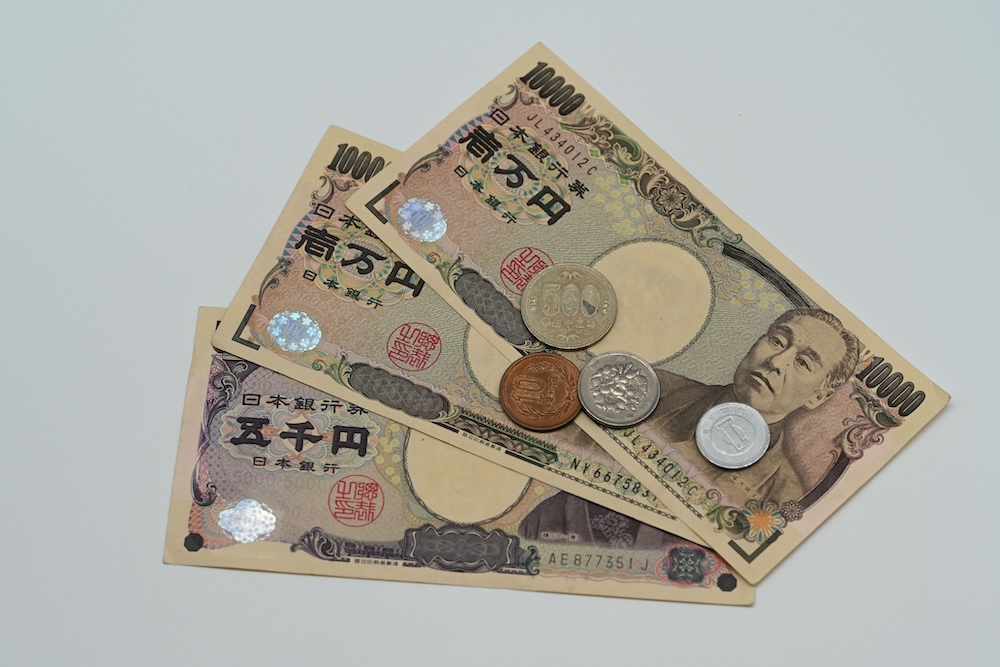 平らな面に並べられた日本円紙幣と硬貨のクローズアップの画像。