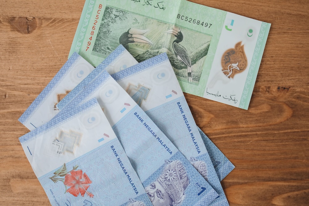木製の背景に展示されたマレーシアリンギットの紙幣の画像。
